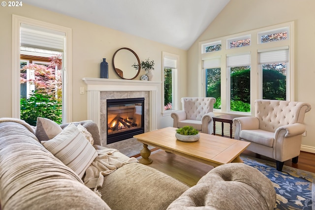 living room with wood-type flooring, a tiled fireplace, and vaulted ceiling