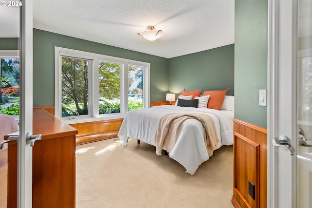 carpeted bedroom with wood walls, a textured ceiling, and french doors