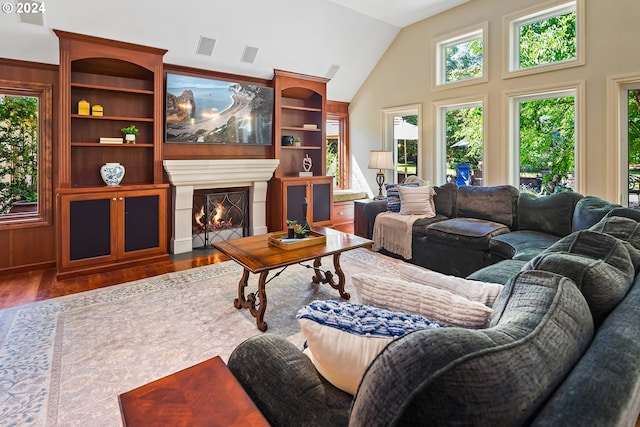 living room with high vaulted ceiling, hardwood / wood-style flooring, and built in features