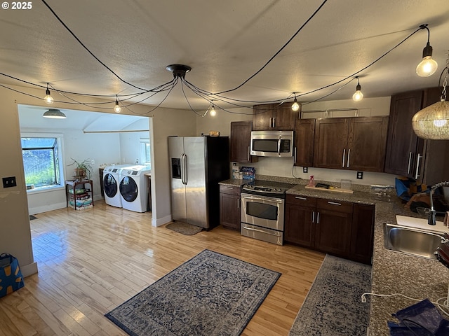 kitchen with sink, light hardwood / wood-style flooring, washing machine and clothes dryer, and appliances with stainless steel finishes