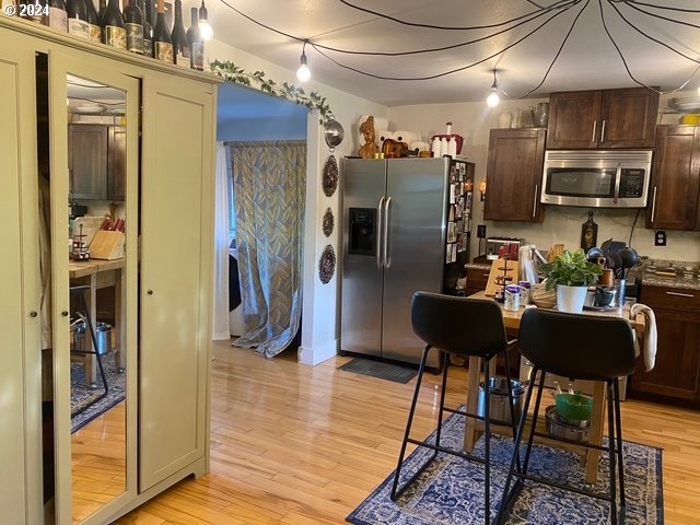 kitchen with dark brown cabinetry, appliances with stainless steel finishes, and light wood-type flooring