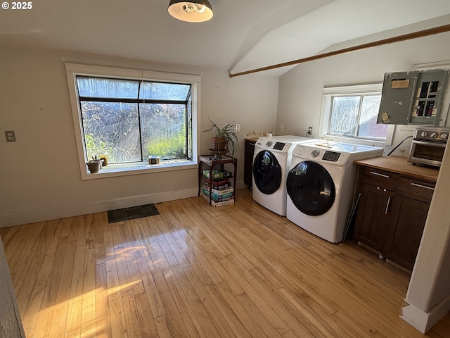 laundry room with washer and dryer, electric panel, and light wood-type flooring