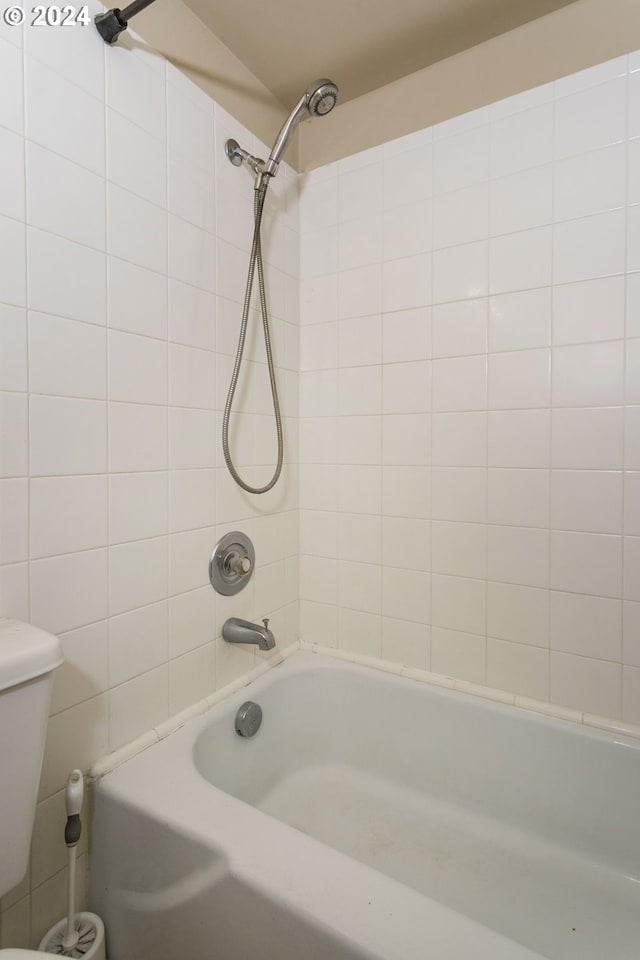 bathroom featuring tiled shower / bath combo and toilet