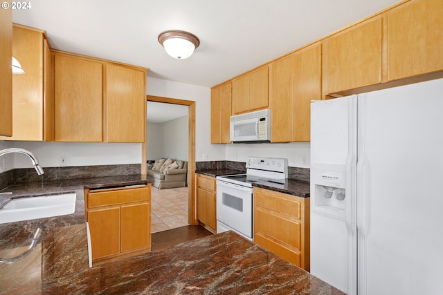 kitchen with sink, tile patterned flooring, dark stone counters, and white appliances