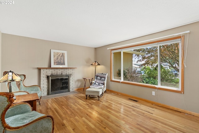 sitting room with light hardwood / wood-style floors, a wealth of natural light, and a brick fireplace