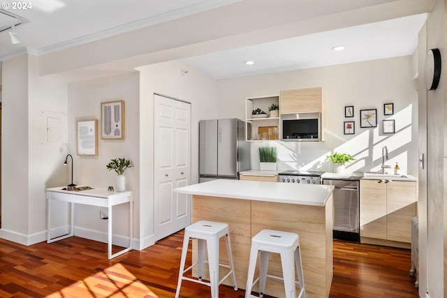 kitchen featuring dark wood-type flooring, a kitchen island, a breakfast bar area, stainless steel appliances, and sink