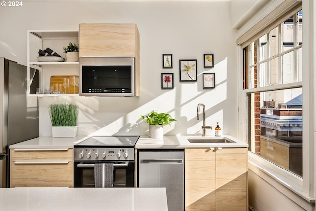 kitchen with light brown cabinetry, stainless steel appliances, and sink