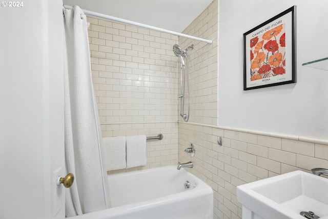 bathroom with tile walls, shower / bath combo, and sink