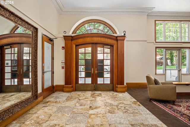 foyer with ornamental molding, a towering ceiling, and french doors