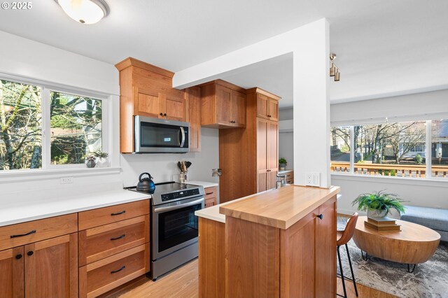 kitchen with butcher block countertops, a kitchen island, stainless steel appliances, and light wood-type flooring