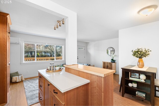 kitchen featuring a wall unit AC, a kitchen island, and light wood-type flooring