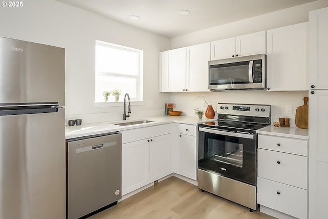 kitchen featuring appliances with stainless steel finishes, light hardwood / wood-style floors, white cabinets, and sink