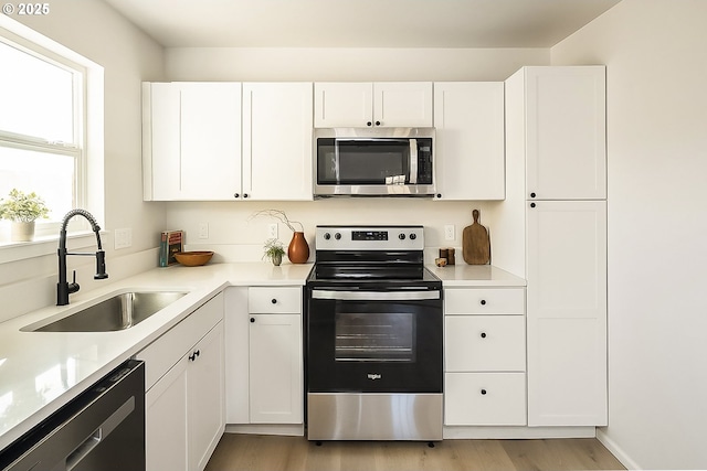 kitchen with light hardwood / wood-style floors, sink, white cabinetry, and appliances with stainless steel finishes