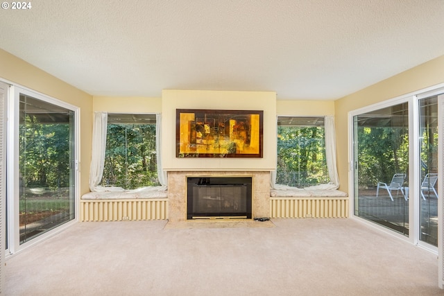 unfurnished living room with a textured ceiling, a high end fireplace, and carpet