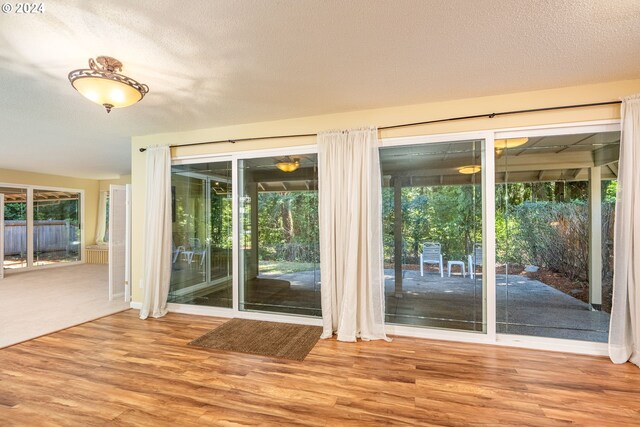 doorway featuring a healthy amount of sunlight, a textured ceiling, and wood finished floors