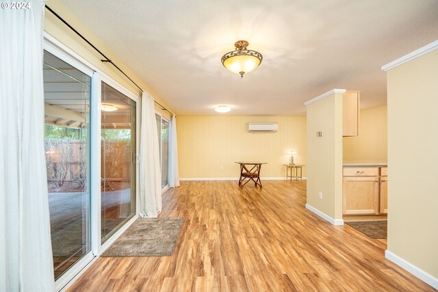 empty room with light wood-style floors, baseboards, and a wall mounted AC