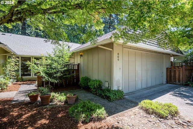 garage featuring aphalt driveway and fence