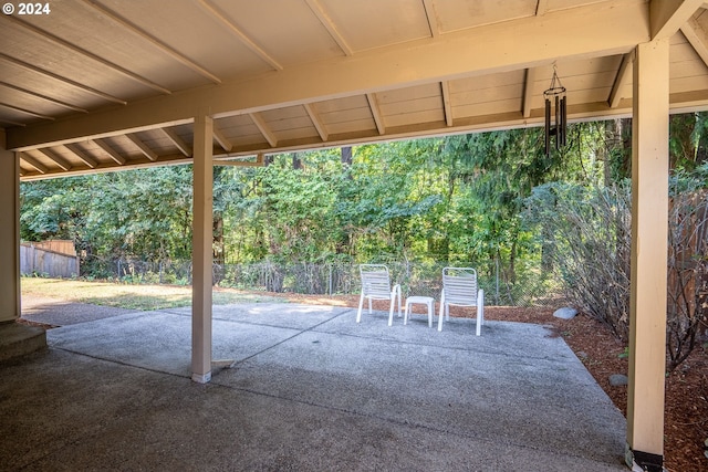 view of patio / terrace featuring a forest view and fence