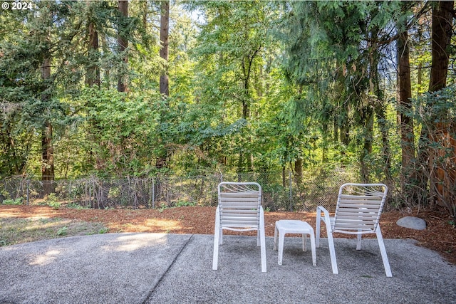 view of patio / terrace featuring a view of trees and fence