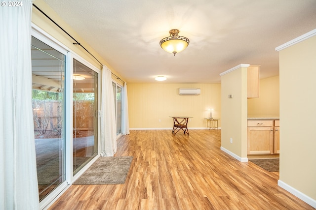 empty room featuring a wall unit AC, baseboards, and light wood-type flooring