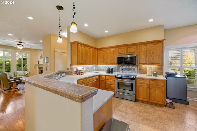 kitchen featuring tasteful backsplash, appliances with stainless steel finishes, pendant lighting, and kitchen peninsula