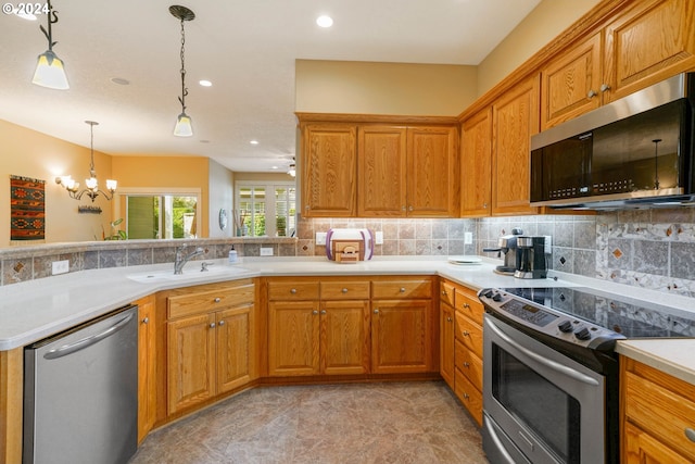 kitchen with sink, tasteful backsplash, appliances with stainless steel finishes, kitchen peninsula, and pendant lighting