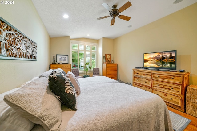 bedroom with ceiling fan, hardwood / wood-style floors, vaulted ceiling, and a textured ceiling