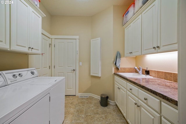 washroom with cabinets, washer and dryer, and sink