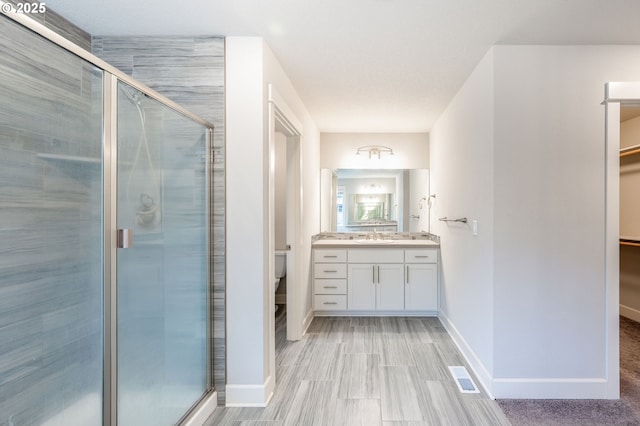 bathroom with toilet, a shower with shower door, and vanity