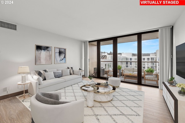 living room with light hardwood / wood-style floors and a wall of windows