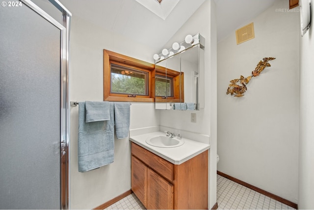 bathroom with vaulted ceiling with skylight, vanity, an enclosed shower, tile patterned floors, and toilet