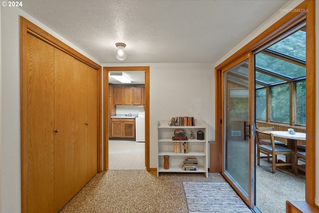 hallway with washer / clothes dryer and a textured ceiling