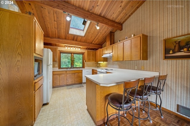 kitchen with a kitchen bar, white appliances, sink, lofted ceiling with skylight, and kitchen peninsula