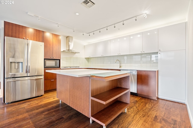 kitchen with stainless steel appliances, hardwood / wood-style flooring, white cabinets, and wall chimney exhaust hood