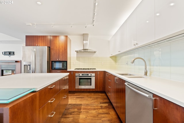 kitchen with wall chimney range hood, sink, white cabinetry, stainless steel appliances, and decorative backsplash