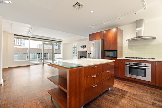 kitchen with stainless steel appliances, track lighting, tasteful backsplash, and wall chimney range hood