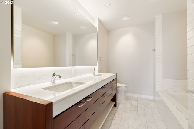 bathroom featuring vanity, tiled tub, and toilet