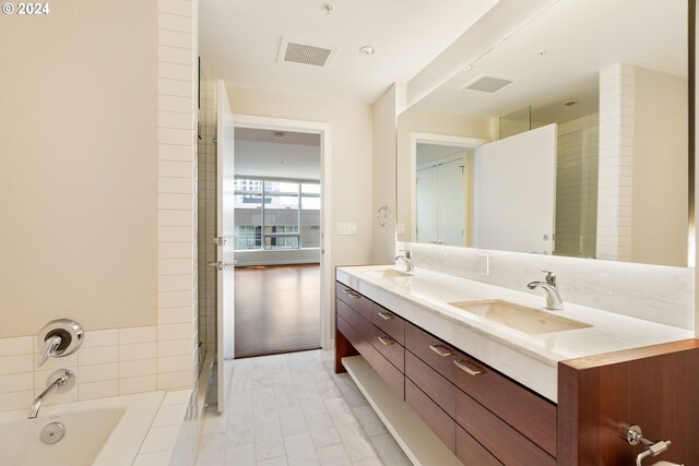 bathroom featuring dual vanity, tile patterned floors, and a tub