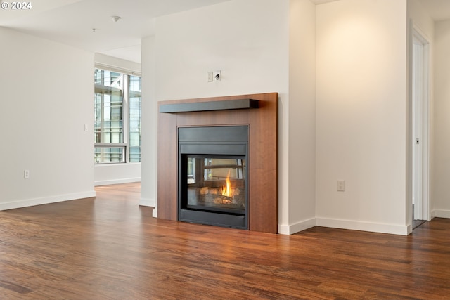 unfurnished living room with dark wood-type flooring and a multi sided fireplace