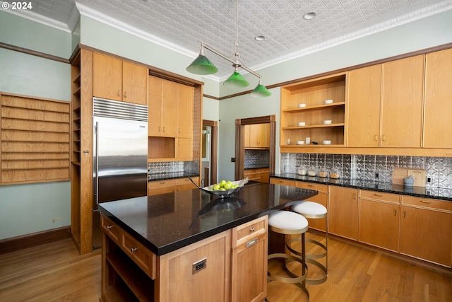 kitchen with light hardwood / wood-style flooring, crown molding, decorative light fixtures, stainless steel built in fridge, and a kitchen island