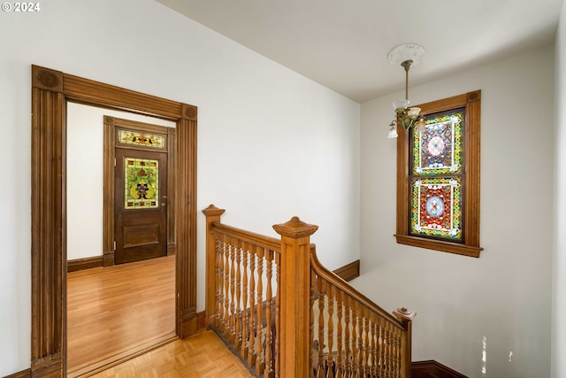 corridor featuring light parquet floors and a notable chandelier