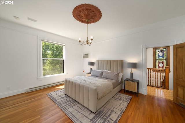 bedroom featuring baseboard heating, an inviting chandelier, and hardwood / wood-style flooring