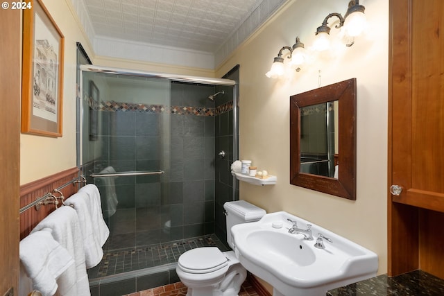 bathroom featuring tile patterned flooring, toilet, a shower with shower door, and ornamental molding