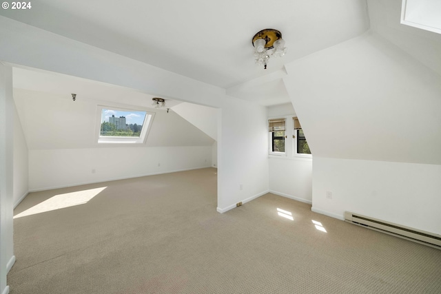 additional living space with baseboard heating, a wealth of natural light, and light carpet