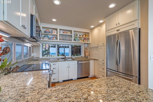 kitchen with light stone counters, sink, white cabinets, and appliances with stainless steel finishes