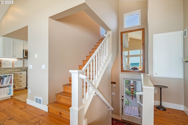 stairway with hardwood / wood-style floors and a towering ceiling