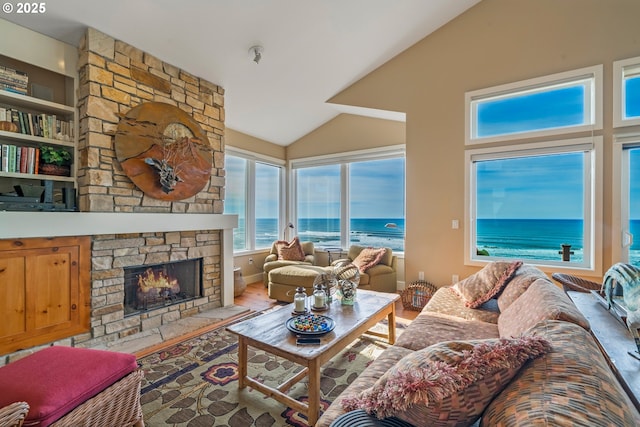 living room featuring a water view, wood-type flooring, built in shelves, a stone fireplace, and vaulted ceiling