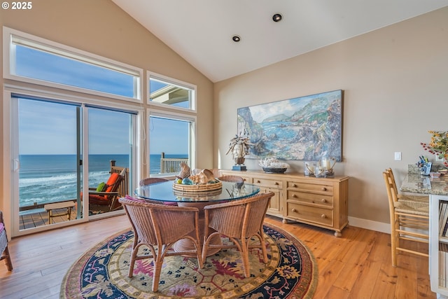 office area featuring a water view, high vaulted ceiling, and light hardwood / wood-style floors