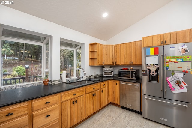 kitchen featuring appliances with stainless steel finishes, lofted ceiling, and sink