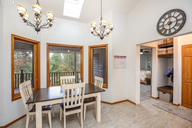 dining area with ceiling fan with notable chandelier, a skylight, and high vaulted ceiling